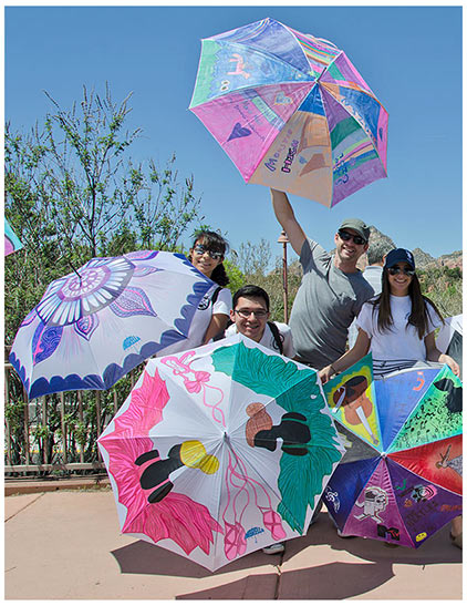 four young adults posing with umbrellas